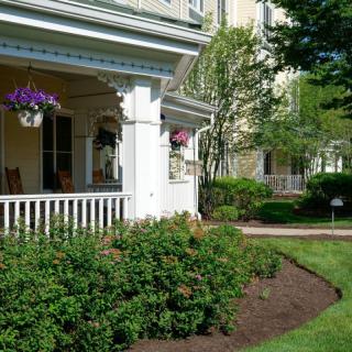 A charming house with a front porch and well-maintained garden, featuring flowers and shrubs.