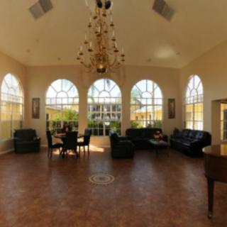 A spacious lounge with large windows, elegant furniture, and a chandelier.
