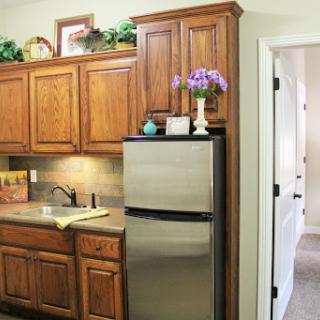 A cozy kitchen featuring wooden cabinets, a stainless steel refrigerator, and a well-organized countertop.