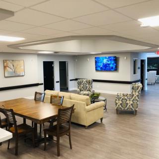A modern lounge area with comfortable seating, a television, and a wooden dining table.