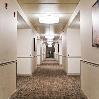 A well-lit, symmetrical hallway with carpeted flooring and ceiling lights.