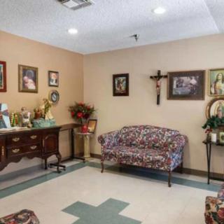 A cozy living room adorned with decorative furniture, religious artwork, and a cross on the wall.
