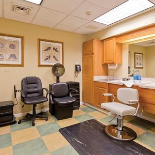 A well-equipped salon room featuring chairs, a mirror, and styling equipment.