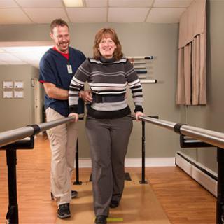 A patient receiving walking assistance from a therapist during a physical therapy session.