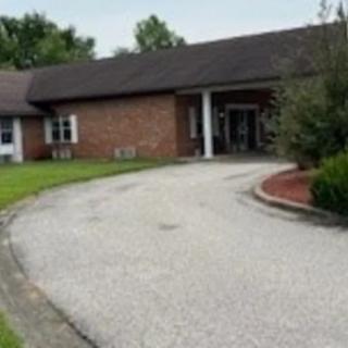 A brick building with a driveway and landscaped entrance.