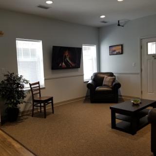 A cozy living room setup featuring a comfortable chair, a television on the wall, and a small table with decorative items.