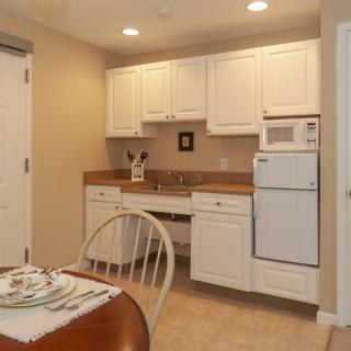 A small kitchen area with white cabinets and a dining table set.