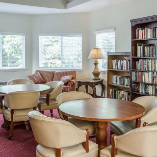 A cozy library reading area with bookshelves, round tables, and comfortable chairs.