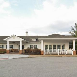 Front view of a residential building with a front porch and parking area.