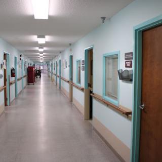 A quiet corridor in a healthcare facility, featuring blue walls and multiple doors.