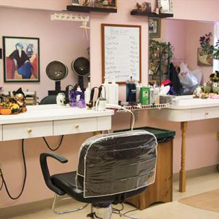 A cozy and well-decorated barbershop interior with a styling chair in front of a mirror surrounded by various beauty products.