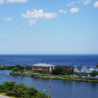 A scenic view of a building by the river, with the ocean and sky in the background.