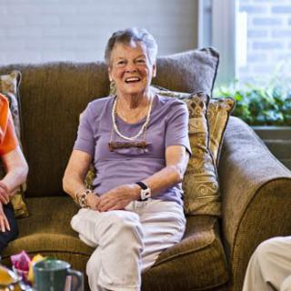 A group of seniors sitting on a couch and enjoying a conversation.