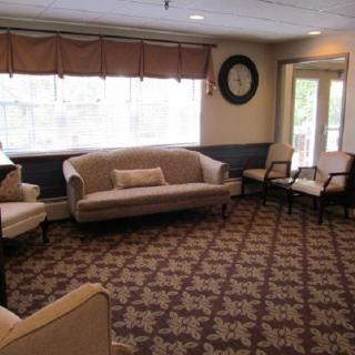 A cozy living room with a sofa, chairs, and a patterned carpet.