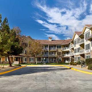 A multi-story residential building with balconies set against a clear blue sky.