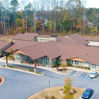 Aerial view of a building with a large parking area and surrounding trees.