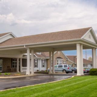 A hotel entrance with a covered driveway and parked cars.