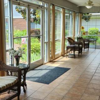 A bright and inviting sunroom with wicker furniture and large windows overlooking a garden.