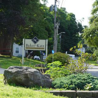 A welcoming sign surrounded by lush greenery, indicating a local establishment.