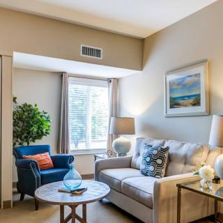 A cozy living room with a sofa, armchair, and coffee table, beautifully lit by natural light from the window.