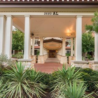 A building entrance with columns and landscaped garden.