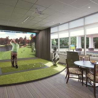 An indoor golf simulator setup with people practicing their swings in a virtual environment.