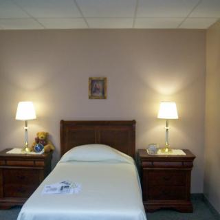 A minimalist hotel room with a single bed and matching nightstands, each with a lamp.