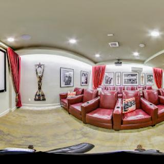 A cozy home theater featuring red leather chairs and framed photographs, perfect for movie nights.
