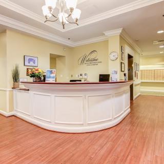 A well-lit reception area with a curved desk and chandelier.