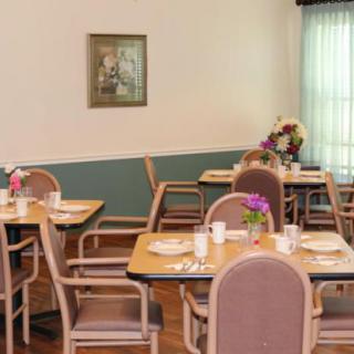 A cozy dining room with neatly arranged tables and chairs, adorned with flowers.