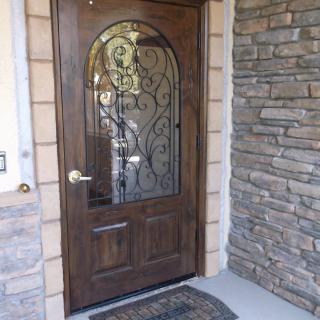 A wooden door with decorative glass set in a stone wall entrance.