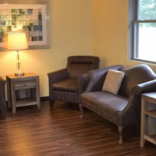 A cozy living room setup with armchairs, a sofa, and a lamp on wooden flooring.