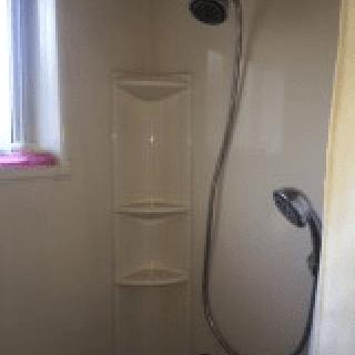 A modern shower setup with a detachable showerhead and built-in shelves.