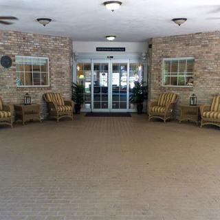 A building entrance with seating arrangements and a brick wall.