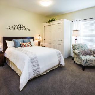 A cozy bedroom featuring a comfortable bed, an armchair, and stylish decor.