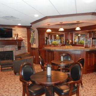 A cozy bar interior with wooden decor, featuring tables, chairs, and a fireplace.