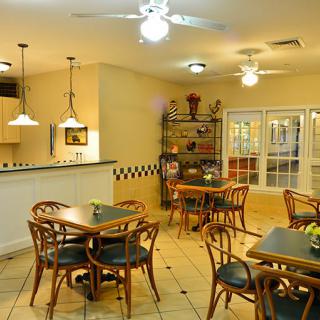 A cozy dining area with wooden tables and chairs, ceiling fans, and warm lighting.