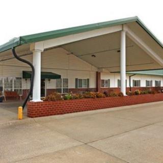 The image shows the entrance of a motel with a covered driveway and brick facade.