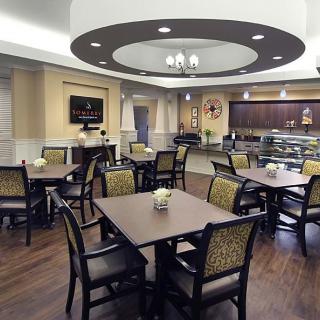 A modern cafe interior with neatly arranged tables and chairs, featuring elegant lighting and decor.