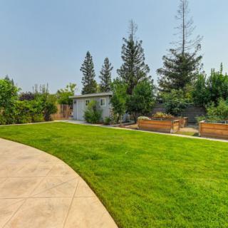 A backyard with a well-maintained lawn, trees, and a garden area.