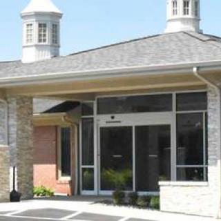 A building entrance with large glass doors and a stone faade under a clear blue sky.