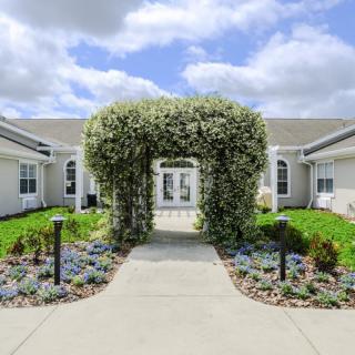 A beautifully landscaped garden with a flowering archway leading to a building.