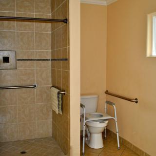 An accessible bathroom with a walk-in shower and supportive handrails.