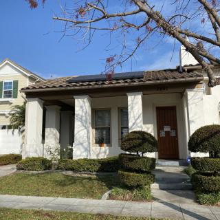 A residential house with solar panels on the roof and a well-maintained garden.