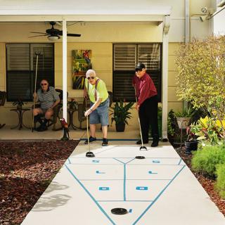 Seniors enjoying a game of shuffleboard on a patio.