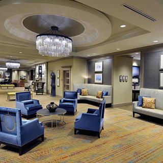 A modern hotel lobby featuring elegant seating arrangements and chandeliers.