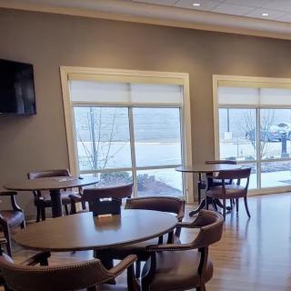 A well-lit dining area with several tables and chairs, featuring large windows that let in natural light.