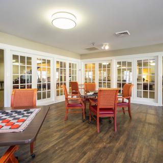 A cozy dining area with wooden floors, red chairs, and glass doors.