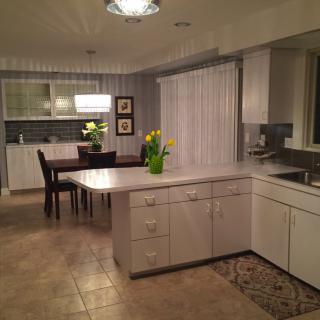 Modern kitchen with an open layout featuring white cabinets, an island, and a dining area.