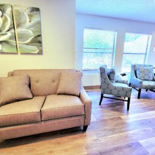 A cozy living room setup featuring a comfortable sofa and stylish chairs, illuminated by natural light.